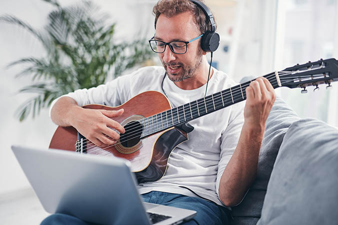 Mann lernt Gitarre auf dem Sofa